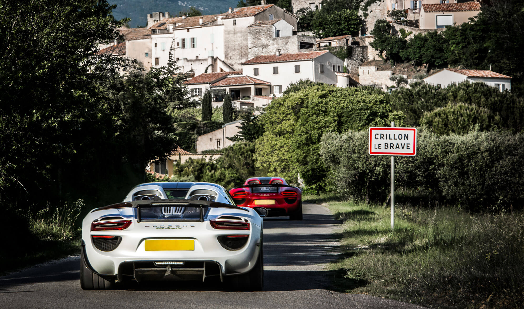 Two Porsche super cars driving into the town of Crillon Le Brave in France