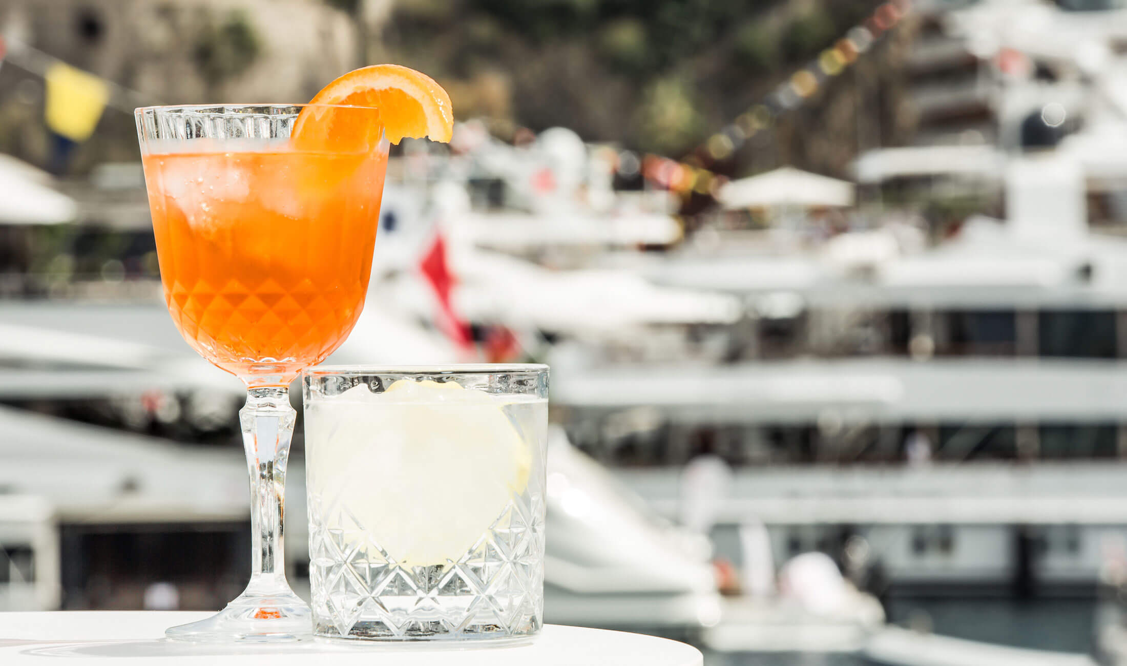 Two alcoholic drinks on table on super yacht in Monaco harbour