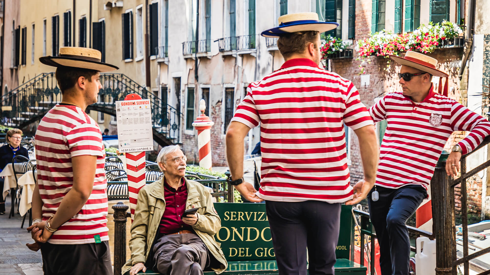 Venetian gondoliers chatting to a local resident on a park bench