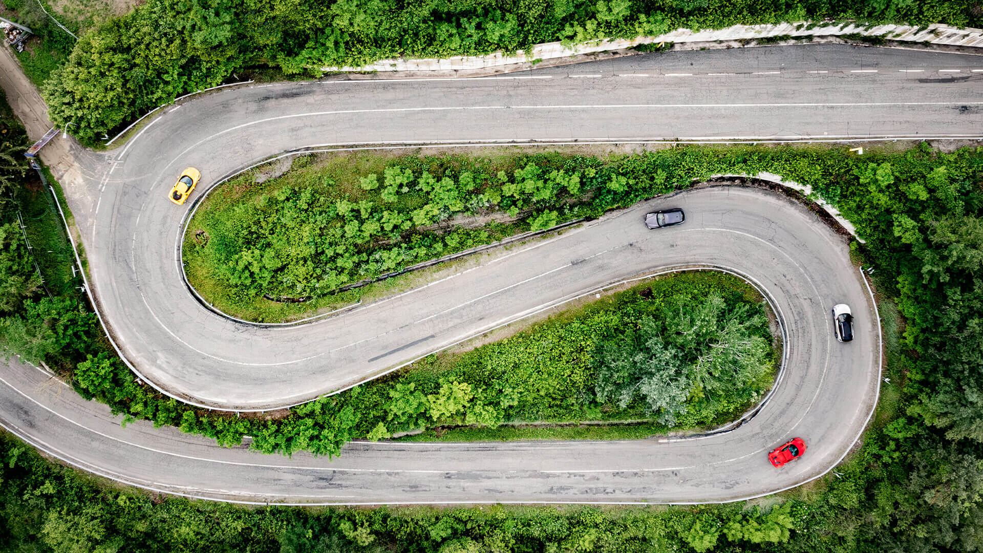 Aerial shot from drone of alpine road and supercars