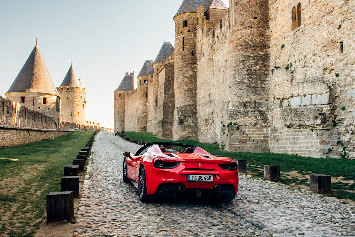 Ferrari driving past the walls of the medieval castle of Carcassonne in France